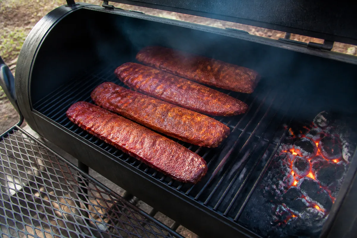 Racks of ribs on the grate of an offset smoker with thin smoke
